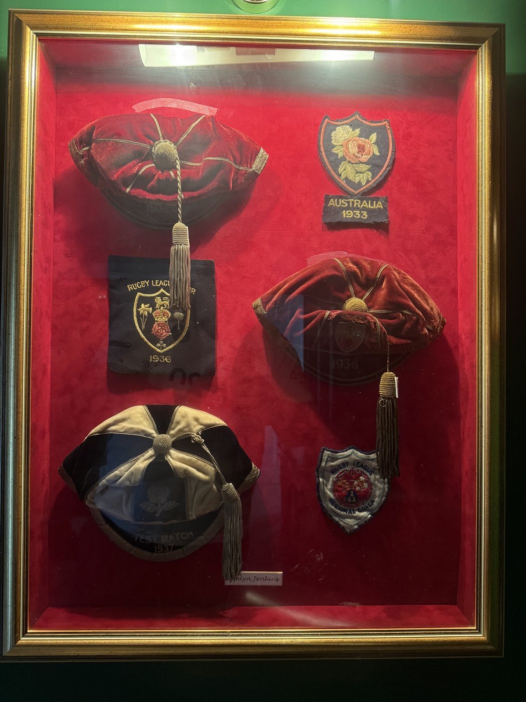 Framed display case of Emlyn Jenkins's surviving rugby league caps and badges
